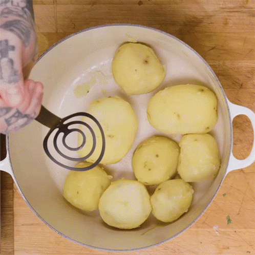 A Person Mashing Potatoes In A White Pot GIF