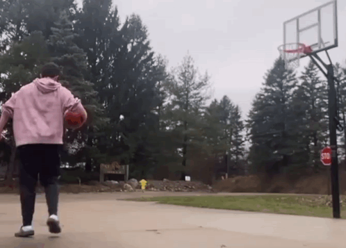 a person playing basketball on a court with a stop sign in the background