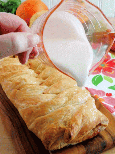 A Person Pouring Milk Into A Pastry On A Wooden Cutting Board GIF