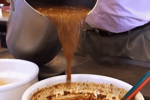 A Person Pouring Something Into A Bowl With A Spoon GIF