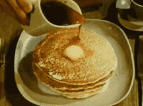 A Person Pouring Syrup On A Stack Of Pancakes GIF