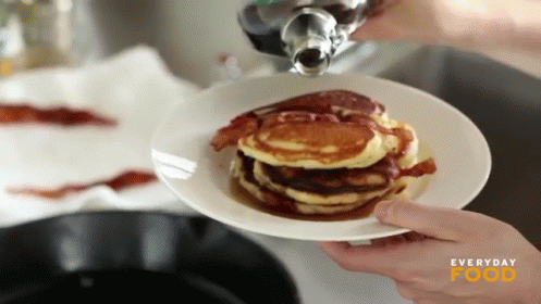 A Person Pouring Syrup On A Stack Of Pancakes With Everyday Food Written On The Bottom GIF