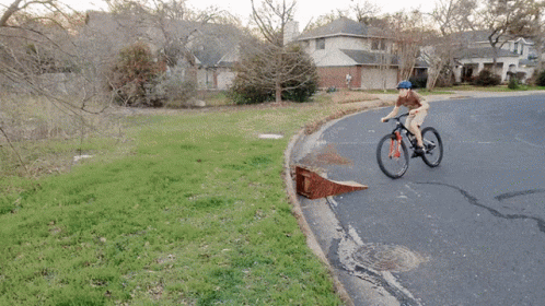 A Person Riding A Bike Down A Road With A Ramp GIF