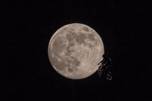 A Person Riding A Bike In Front Of The Moon GIF