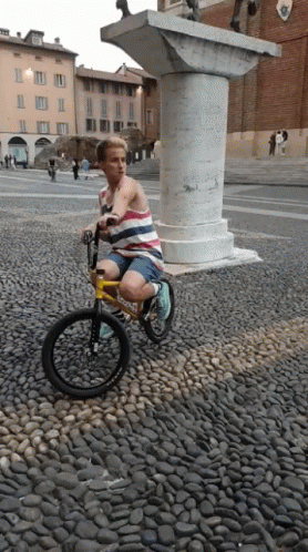 A Person Riding A Bike On A Cobblestone Street GIF