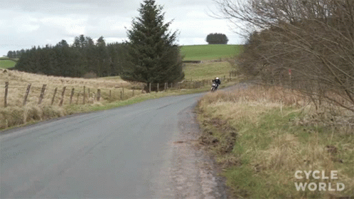 A Person Riding A Motorcycle Down A Road That Says Cycle World On It GIF