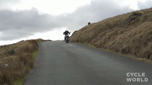 A Person Riding A Motorcycle Down A Road With Cycle World Written On The Bottom Right GIF