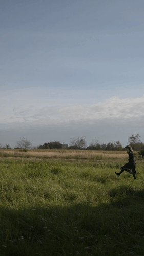 a person running in a field with trees in the background