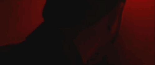A Person 'S Arm Is Visible In A Dark Room With A Red Light Behind Them . GIF