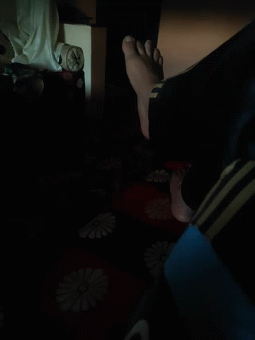A Person 'S Feet Are Standing On A Red And Black Blanket With Flowers On It GIF