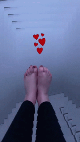 A Person 'S Feet Are Standing On A Staircase With Red Hearts Floating Above Them GIF