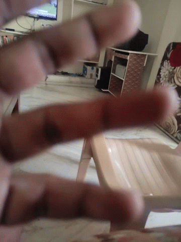 A Person 'S Fingers Are Visible In A Blurry Photo With A Chair In The Background GIF