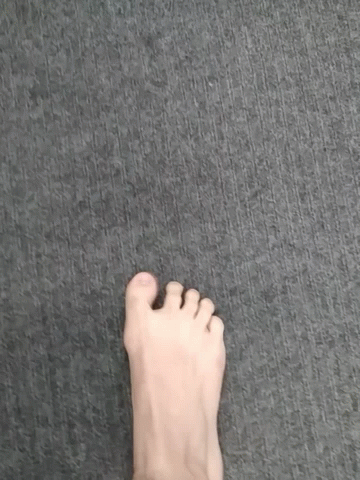 A Person 'S Foot Is Standing On A Gray Carpet . GIF