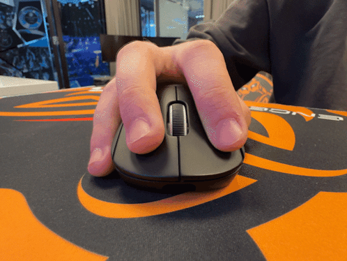 A Person 'S Hand Is Holding A Computer Mouse On An Orange And Black Mouse Pad GIF