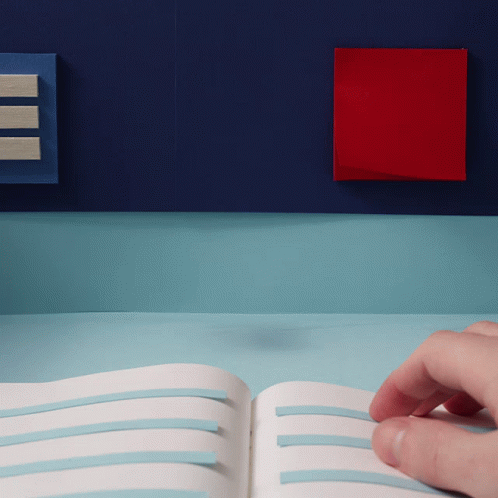 A Person 'S Hand Is Holding An Open Book With Blue Stripes On It GIF