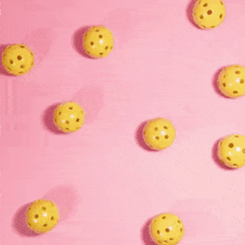 A Person 'S Hand Is Reaching For A Yellow Ball On A Pink Background . GIF