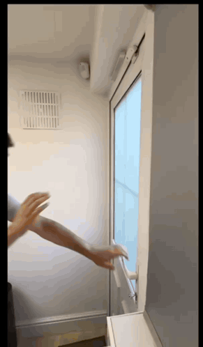 A Person 'S Hand Is Reaching Out To Open A Window GIF