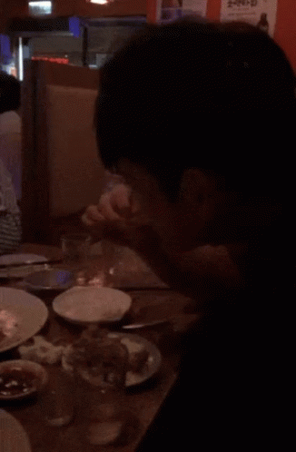 A Person Sitting At A Table With Plates Of Food And A Sign That Says ' Ae ' On It GIF