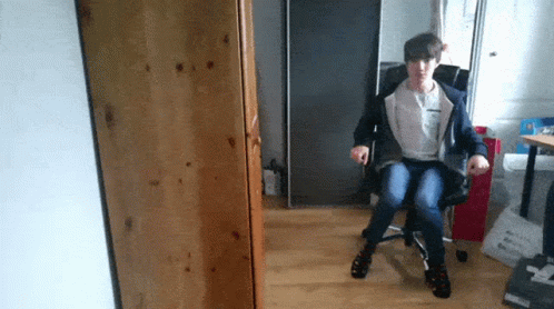 A Person Sitting In A Chair With The Letter T On The Back Of Their Shirt GIF