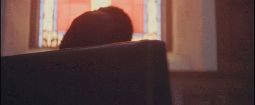 A Person Sitting In A Church Looking Out A Window GIF