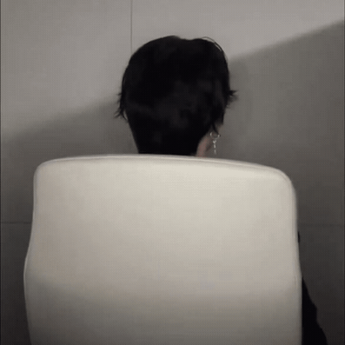 A Person Sitting In A White Chair With Their Head Visible GIF
