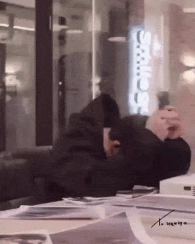 A Person Sitting In Front Of A Sign That Says ' Adidas ' GIF