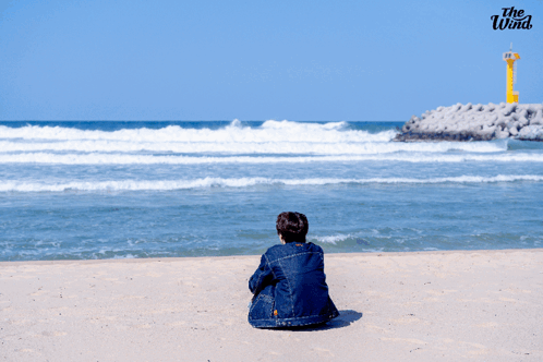A Person Sitting On A Beach With The Wind Written On The Bottom Right GIF