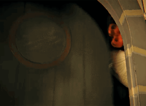 A Person Standing In A Dark Room With A Red Mask On Their Head GIF