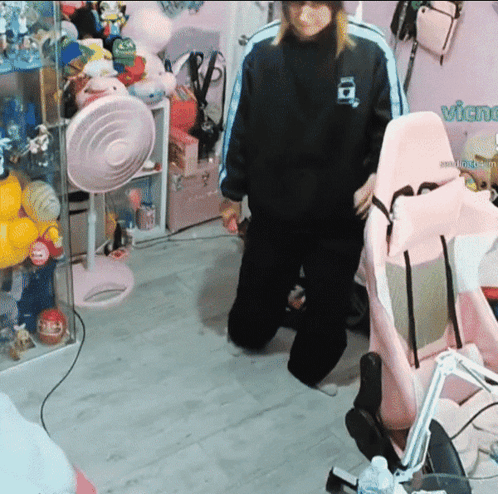 A Person Standing In A Room With A Pink Chair And A Sign That Says Vichu GIF