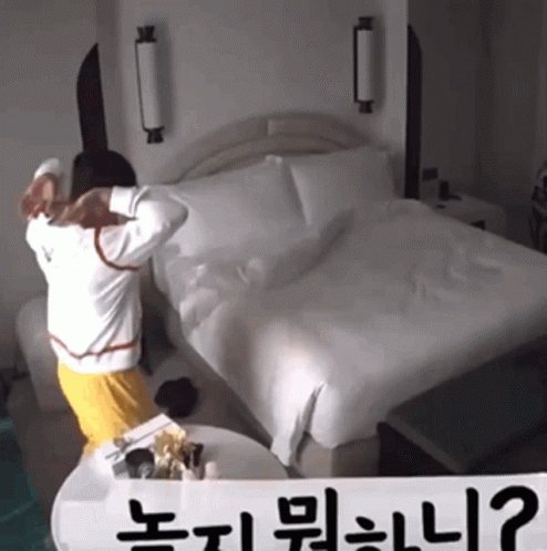 A Person Standing In Front Of A Bed With A Sign That Says " ? " GIF