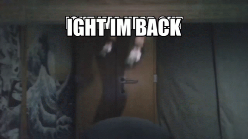 A Person Standing In Front Of A Door With The Words Ight I 'M Back Written Above Them GIF
