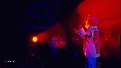 A Person Standing In Front Of A Microphone With The Word Cancella On The Bottom Right GIF