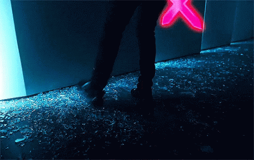 A Person Standing On A Broken Glass Floor With A Neon Sign In The Background . GIF