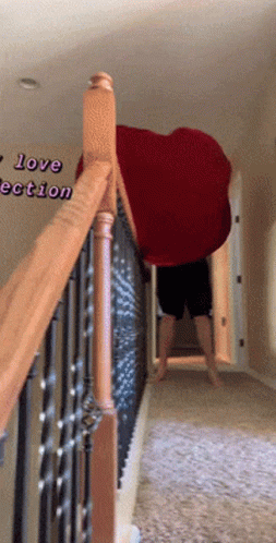 A Person Standing On A Set Of Stairs Holding A Large Red Heart Shaped Blanket GIF