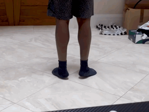 A Person Standing On A Tiled Floor Wearing A Pair Of Socks GIF