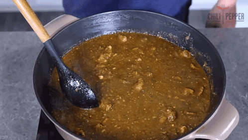 A Person Stirring A Pot Of Chili Pepper Sauce With A Black Spoon GIF