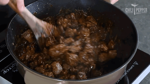 A Person Stirring A Pot Of Food With A Wooden Spoon And The Words Chili Pepper On The Bottom Right GIF