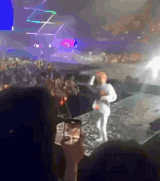 A Person Taking A Picture Of A Person On Stage With A Cell Phone GIF