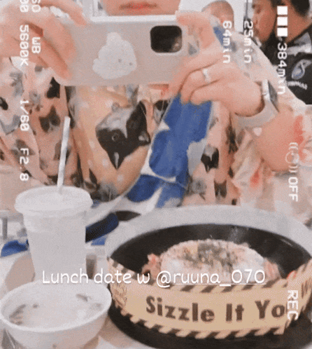 A Person Taking A Picture Of A Plate Of Food With A Sign That Says Sizzle It You On It GIF