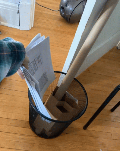 A Person Throws A Piece Of Paper Into A Trash Can That Says ' Papers ' On It GIF