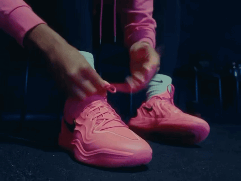 A Person Tying Their Pink Nike Shoes With White Socks GIF