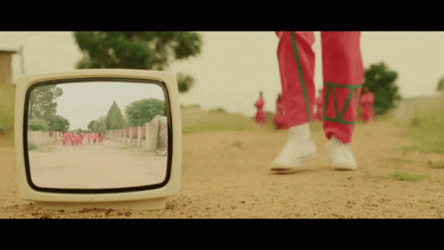 A Person Walking Down A Dirt Road Is Reflected In A Television Screen GIF
