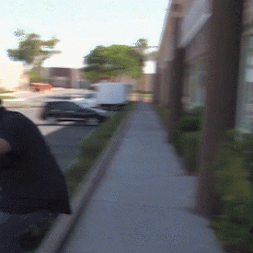 A Person Walking Down A Sidewalk With A Bag On Their Back GIF