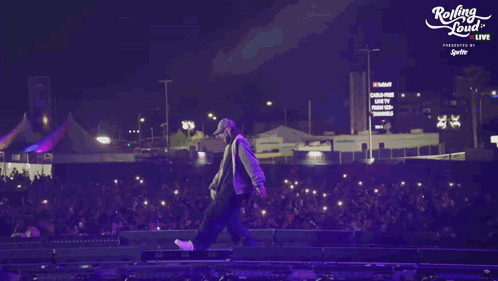 A Person Walking On A Stage With A Rolling Loud Logo In The Background GIF