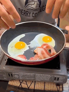 A Person Wearing A Berry College Shirt Is Cooking Eggs And Bacon GIF
