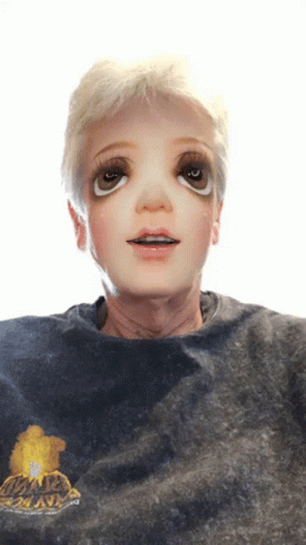 A Person Wearing A Black Shirt With A Yellow Flower On It Has A Doll Face On Their Face GIF