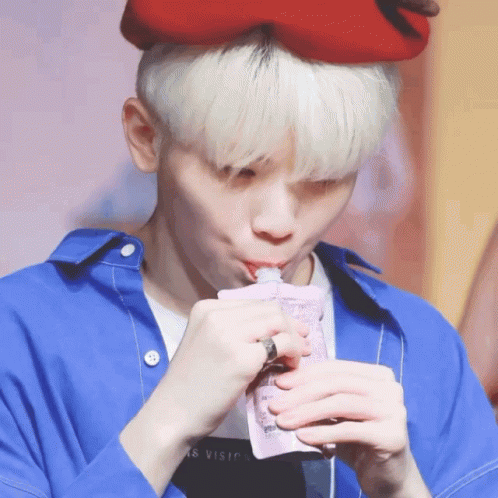 A Person Wearing A Blue Shirt And A Red Hat Drinking From A Bag GIF
