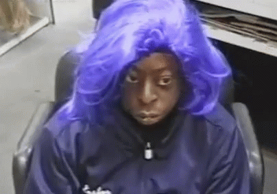 A Person Wearing A Blue Wig Is Sitting In A Chair . GIF