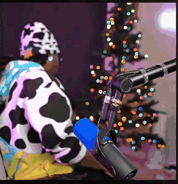 A Person Wearing A Cow Costume Is Sitting In Front Of A Microphone . GIF
