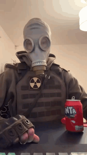 A Person Wearing A Gas Mask Holds A Can Of Fanta GIF